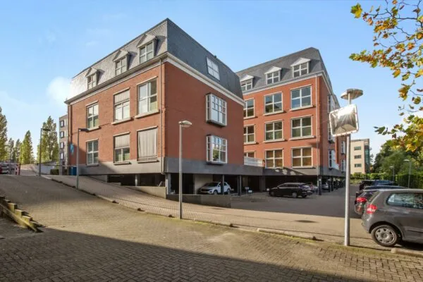 Modern rood bakstenen kantoorgebouw aan de Laan van Vredenoord met ondergelegen parkeergarage en omliggende parkeerplaatsen.